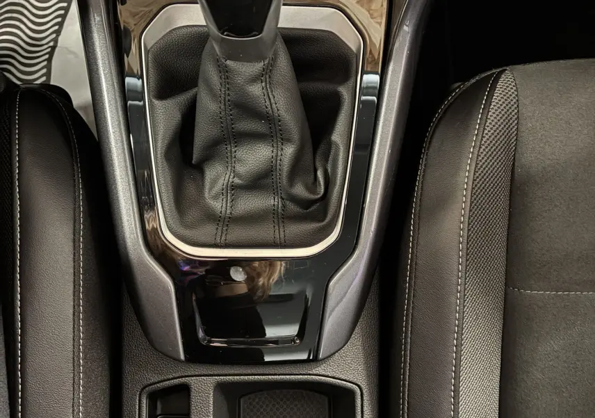Vue plongeante sur la console centrale noire du Volkswagen T-Roc 2025, mettant en valeur le levier de vitesse automatique et les commandes adjacentes.