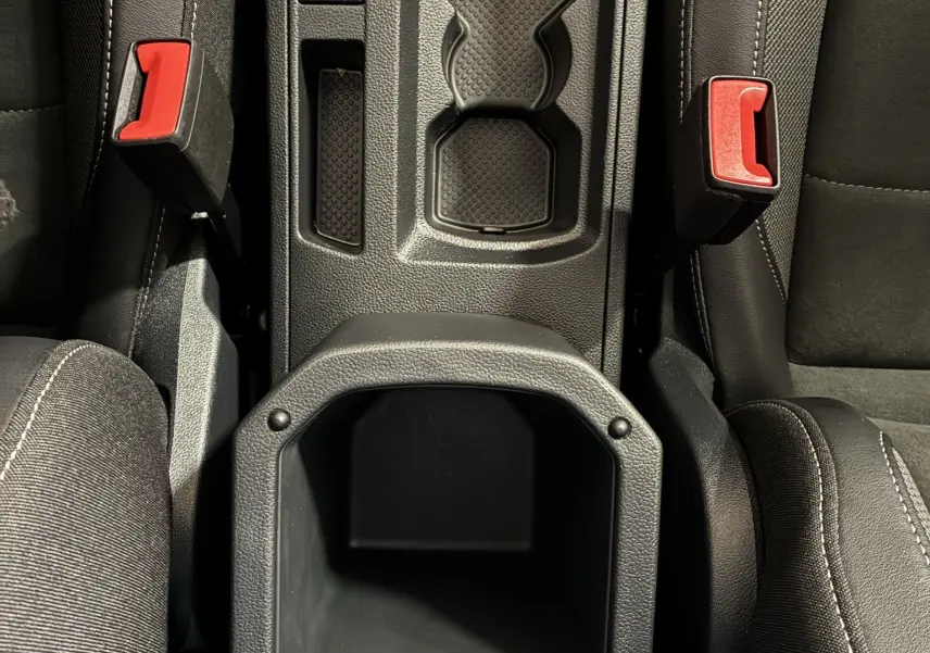 Vue plongeante sur la console centrale noire du Volkswagen T-Roc 2025, avec porte-gobelets et boutons électroniques visibles.