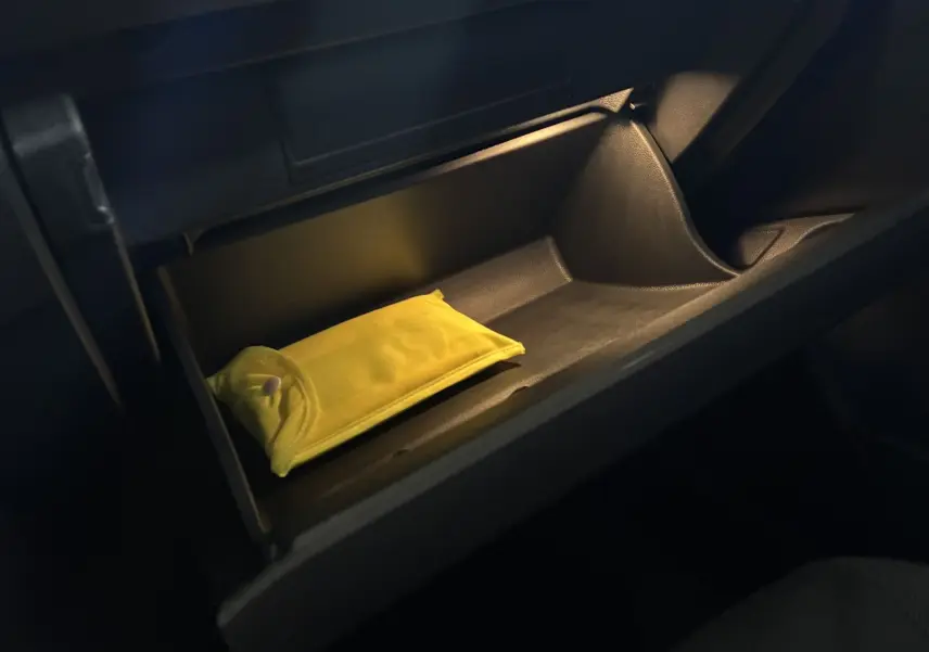 Vue intérieure du vide-poche côté passager du Volkswagen T-Roc noir 2025, avec un étui jaune à l'intérieur.
