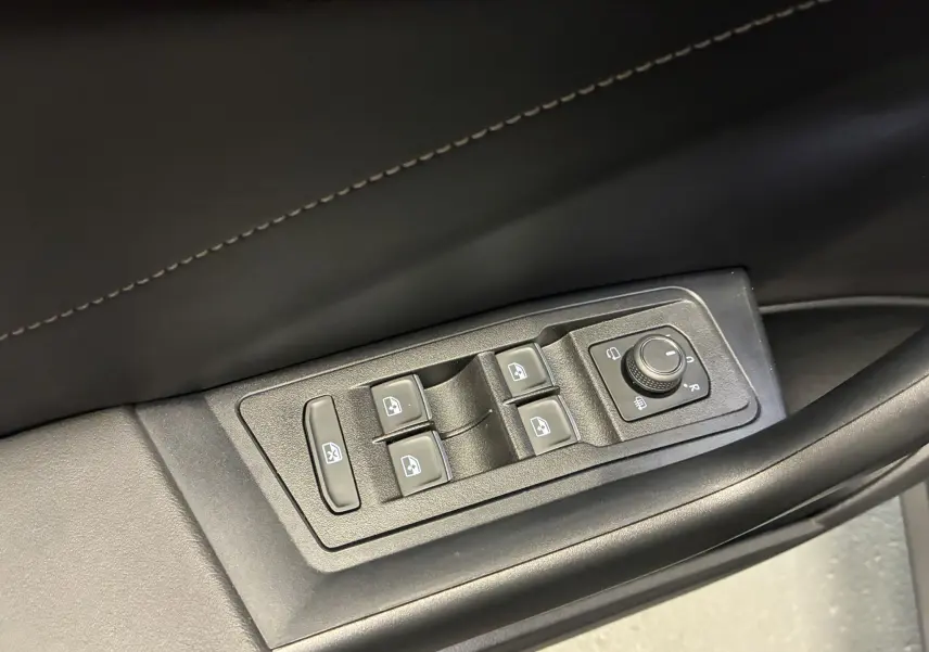 Vue rapprochée des commandes des vitres et réglages des rétroviseurs sur la porte côté gauche d’un Volkswagen T-Roc noir.