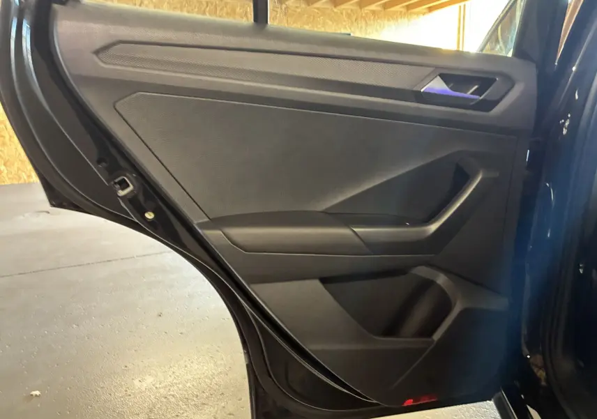Vue intérieure de la porte arrière gauche noire du Volkswagen T-Roc 2025, avec poignée et rangements intégrés.