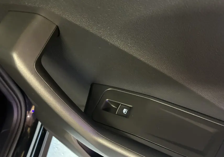Gros plan sur le bouton de commande de la vitre électrique côté intérieur de la porte noire du Volkswagen T-Roc 2025.