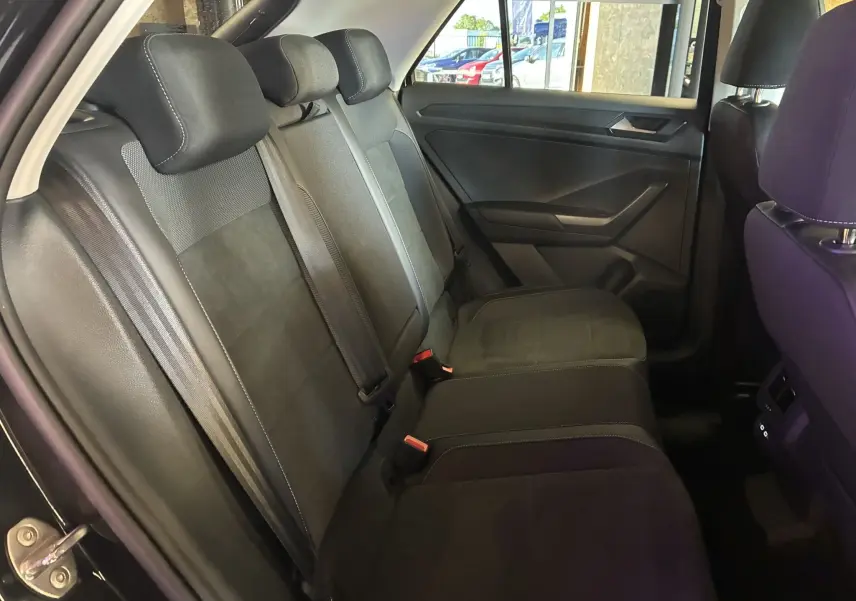 Vue intérieure côté gauche des sièges arrière noirs en tissu du Volkswagen T-Roc 2025, avec ceintures et appuie-têtes visibles.