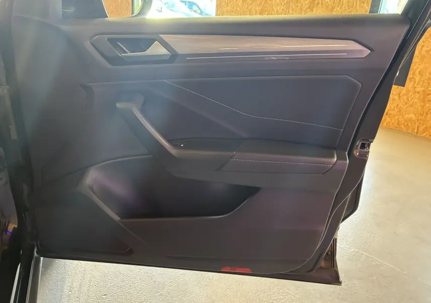 Vue intérieure de la porte avant droite noire du Volkswagen T-Roc 2025, avec garniture en tissu noir et surpiqûres contrastantes.