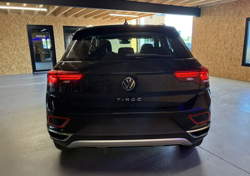 Vue arrière d'un Volkswagen T-Roc noir 2025 avec feux LED allumés dans un garage intérieur.