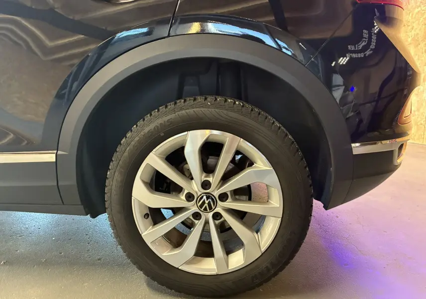 Gros plan sur la roue arrière droite d’un Volkswagen T-Roc noir 2025, mettant en valeur la jante aluminium et le passage de roue.