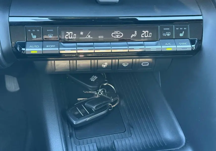 Vue rapprochée de la console centrale du Toyota C-HR 2025, montrant les commandes de climatisation et un porte-clés noir posé.