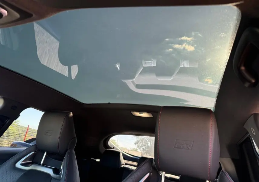 Vue intérieure arrière du Toyota C-HR 2.0 Hybride GR Sport avec toit panoramique et sièges sport noirs à surpiqûres rouges.