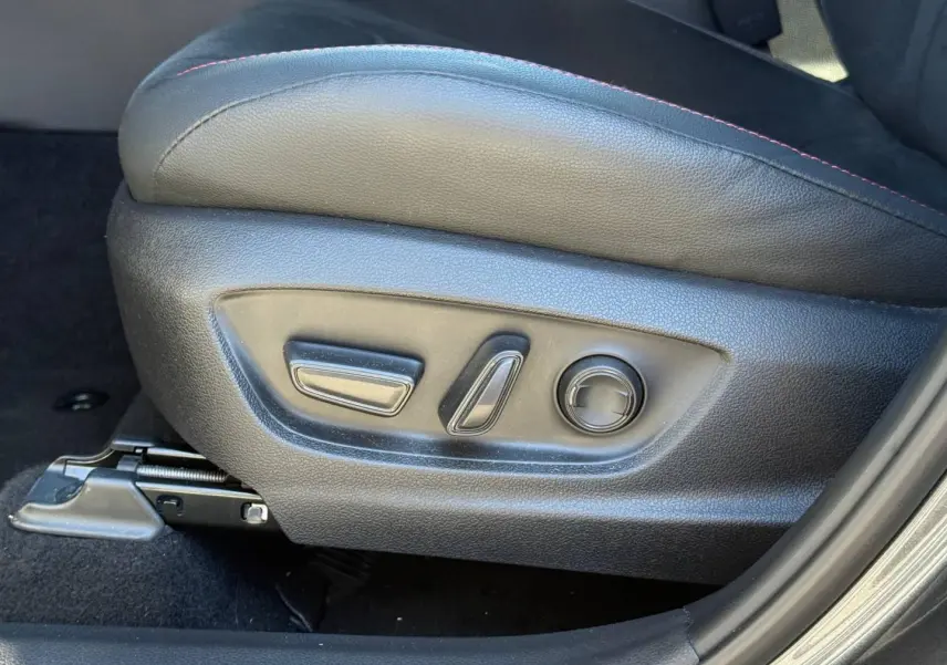 Gros plan sur les commandes électriques du siège conducteur en cuir noir avec surpiqûres rouges du Toyota C-HR GR Sport 2025.