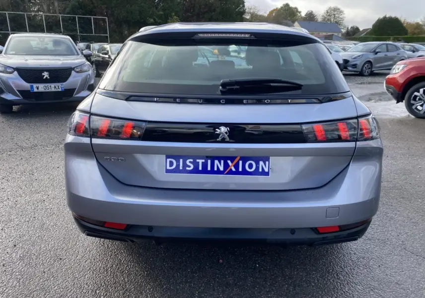 Vue arrière d'un Peugeot 508 SW gris Artense avec feux arrière à effet griffes et logo distinctif au centre.