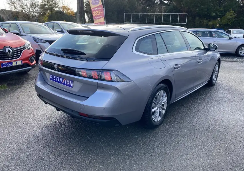 Peugeot 508 SW gris Artense vue 3/4 arrière droit, break diesel avec feux arrière à griffes distinctifs.