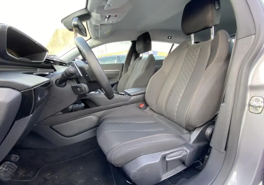 Vue intérieure côté conducteur de la Peugeot 508 SW gris Artense, sièges avant en tissu noir avec surpiqûres contrastées.