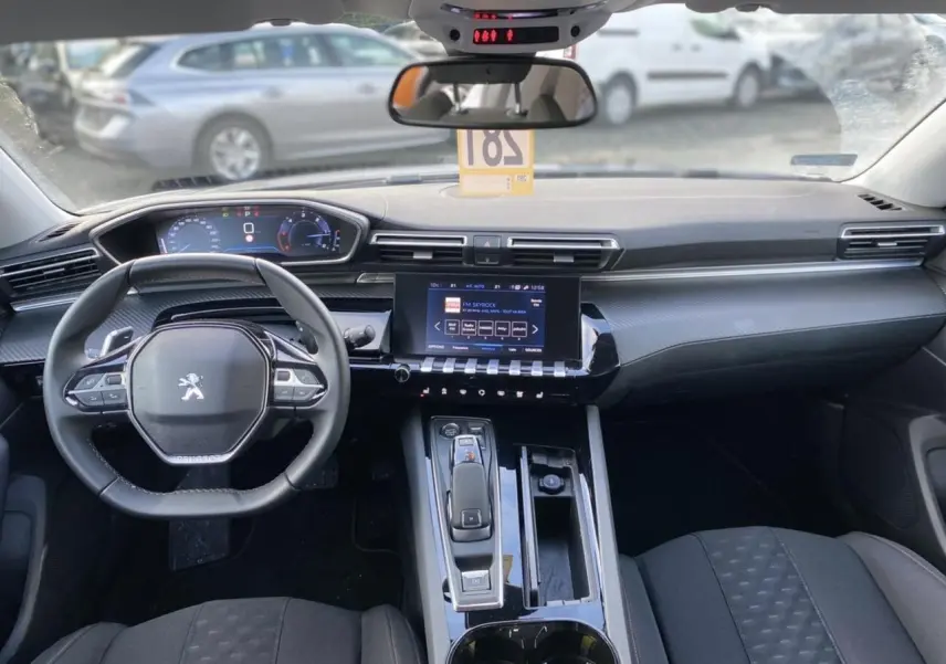 Intérieur de Peugeot 508 SW 2021 vu de face, tableau de bord moderne avec écran tactile et volant compact noir.
