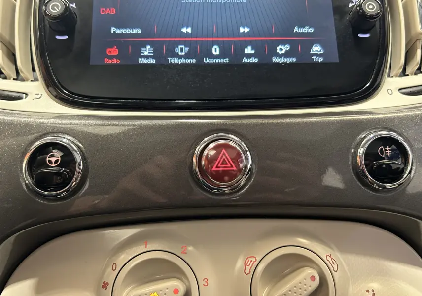Gros plan sur la console centrale grise du tableau de bord du Fiat 500 70 Hybride BSG DolceVita avec écran tactile et commandes circulaires.