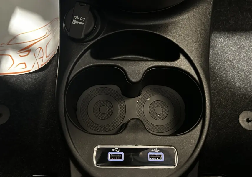 Vue plongeante sur la console centrale noire de la Fiat 500 avec porte-gobelets et deux ports USB éclairés.