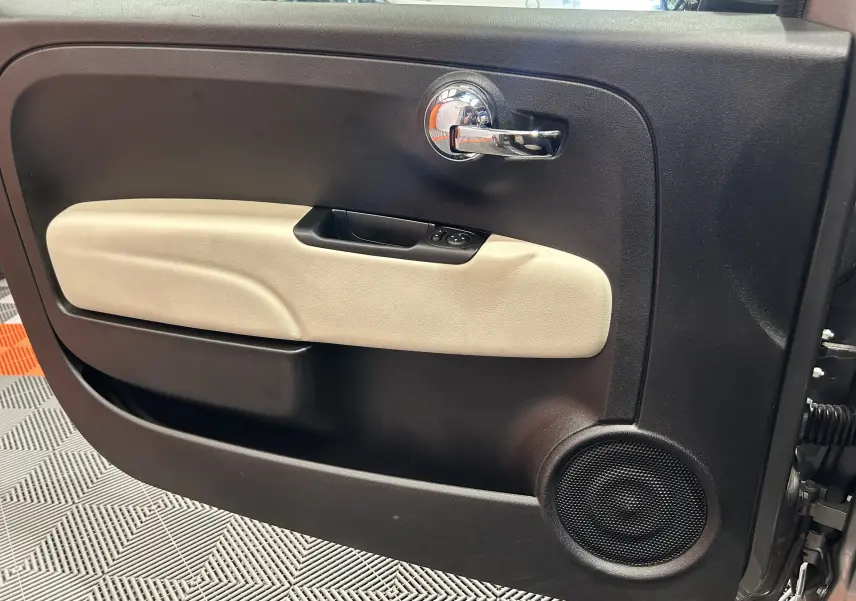 Intérieur de la porte côté gauche de la Fiat 500 gris, avec poignée chrome et habillage beige clair.