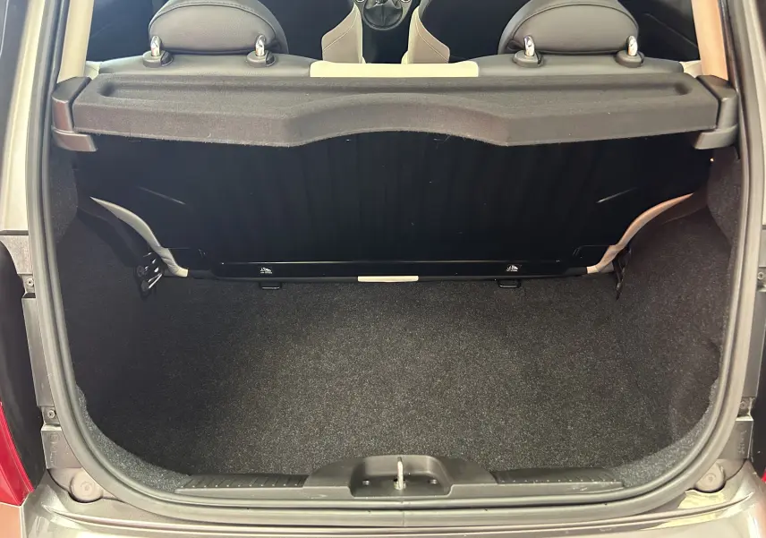 Vue arrière du coffre ouvert d'une FIAT 500 gris 70 Hybride BSG Dolcevita avec banquette arrière et habillage noir.
