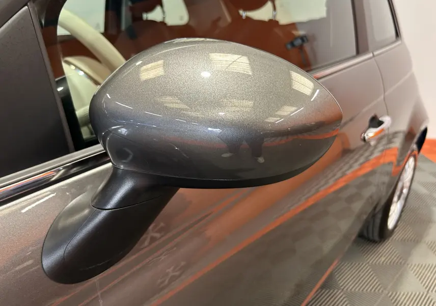 Rétroviseur côté gauche gris métallisé de la Fiat 500 hybride 2022, avec portière et partie avant visibles en léger flou.
