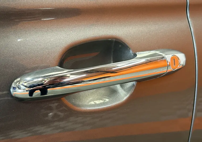 Poignée de porte chromée sur la portière gris métallisé d'une FIAT 500 70 Hybride BSG DolceVita, vue en gros plan.
