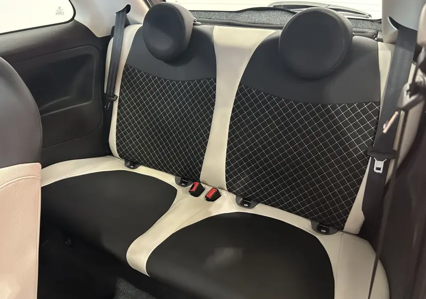 Vue intérieure arrière des sièges bicolores noir et blanc avec surpiqûres en losange d'une Fiat 500 70 Hybride BSG Dolcevita 2022.