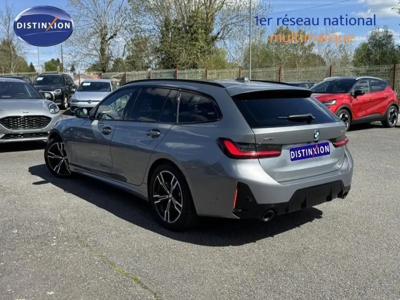 BMW Série 3 320dA xDrive M Sport grise Skyscrapergrau vue 3/4 arrière gauche sur parking extérieur.