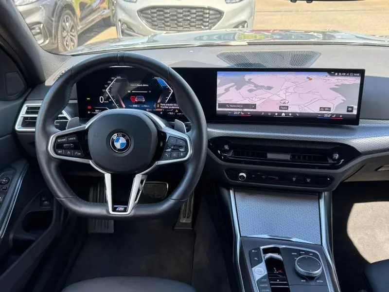 Vue intérieure du poste de conduite de la BMW Série 3 320dA xDrive M Sport 2025 avec écran large et volant multifonction noir.