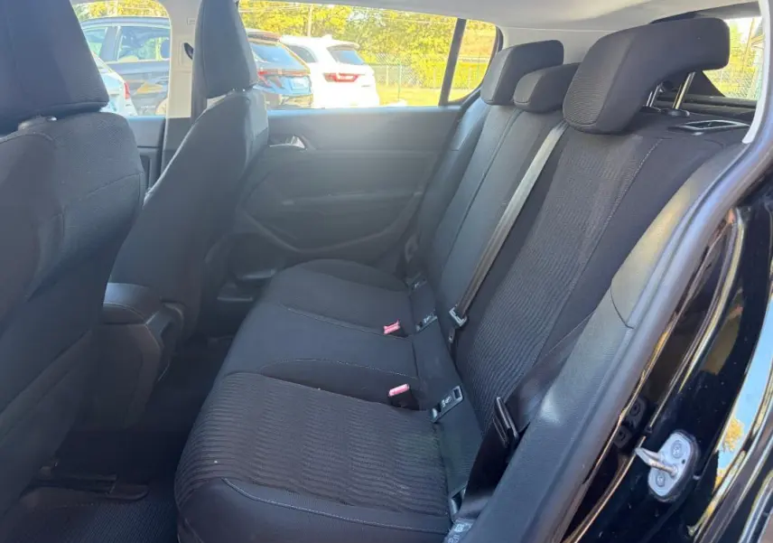 Vue intérieure côté droit des sièges arrière noirs d'une Peugeot 308 Active 2014 avec ceintures de sécurité visibles.