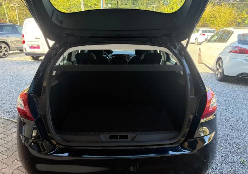 Vue arrière d'une Peugeot 308 Active noire de 2014 avec coffre ouvert, montrant l'espace de chargement vide.