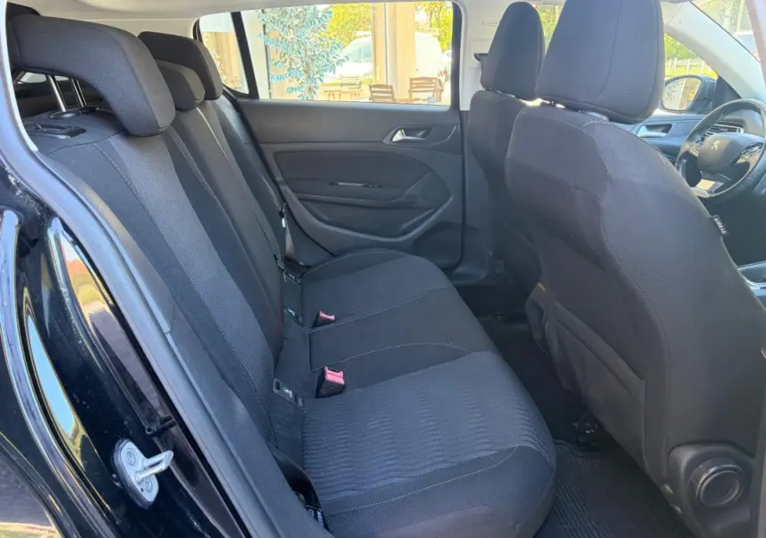 Intérieur arrière de la Peugeot 308 Active 2014 noir, vue côté gauche montrant les sièges en tissu et la portière ouverte.