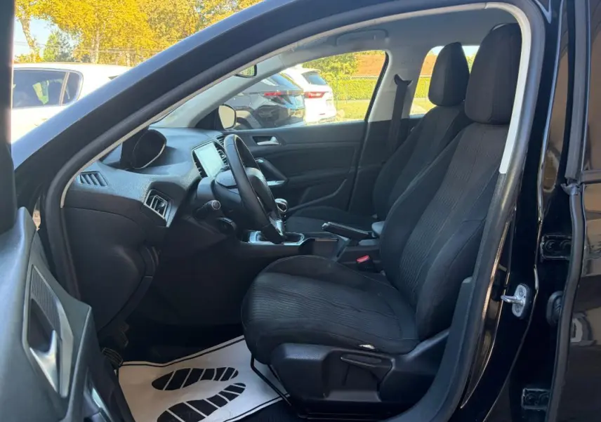 Intérieur côté conducteur d'une Peugeot 308 Active noire 2014, montrant sièges avant et tableau de bord.