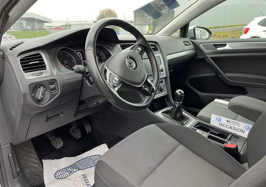 Intérieur noir de Volkswagen Golf 7 2017, vue côté conducteur montrant volant, tableau de bord et levier de vitesse manuel.
