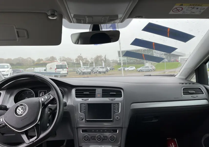 Vue intérieure avant de la Volkswagen Golf 7 argentée de 2017, montrant le tableau de bord et le volant multifonction noir.