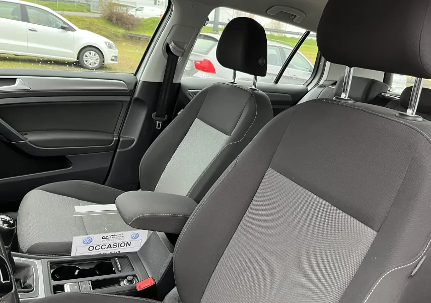 Intérieur de la Volkswagen Golf 7 2017 en tissu noir et gris, vue côté conducteur avec accoudoir central et levier de vitesse manuel.