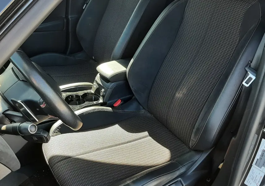 Vue intérieure côté conducteur du DS3 Crossback gris foncé, mettant en valeur les sièges en tissu et cuir noir avec console centrale entre les deux.