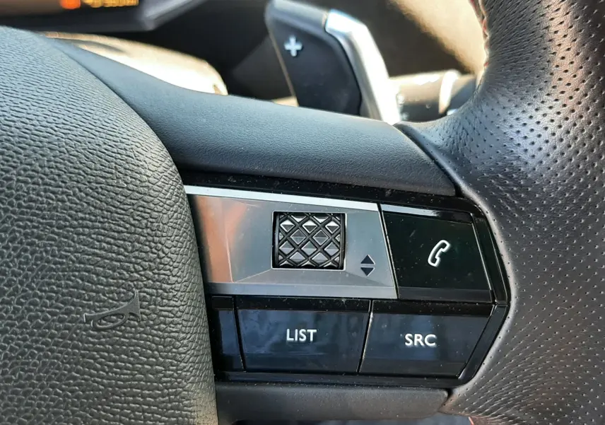 Gros plan sur les commandes gauche du volant en cuir perforé noir du DS3 Crossback gris foncé, avec molette et boutons fonction téléphone.
