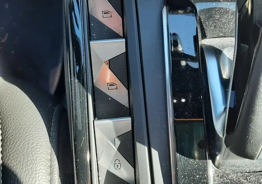 Gros plan sur les boutons de verrouillage centralisé et lève-vitres côté conducteur du DS3 Crossback gris foncé, intérieur noir.