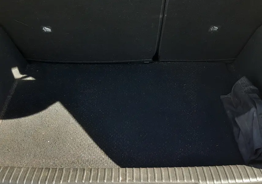 Coffre ouvert vu de face d'un DS3 Crossback gris foncé, montrant un espace de chargement vide avec un tissu noir.