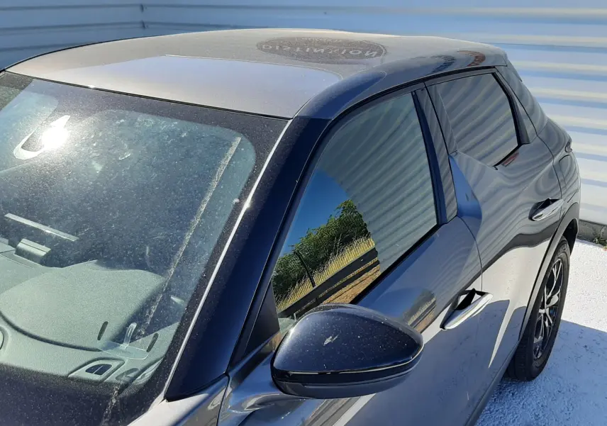Vue 3/4 avant droit d'un DS3 Crossback gris foncé avec vitres teintées et rétroviseur noir brillant.