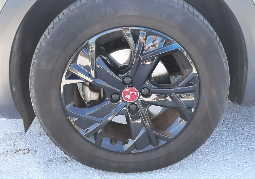 Gros plan sur la roue avant droite du DS3 Crossback gris foncé, jante alliage noire au logo DS rouge central.