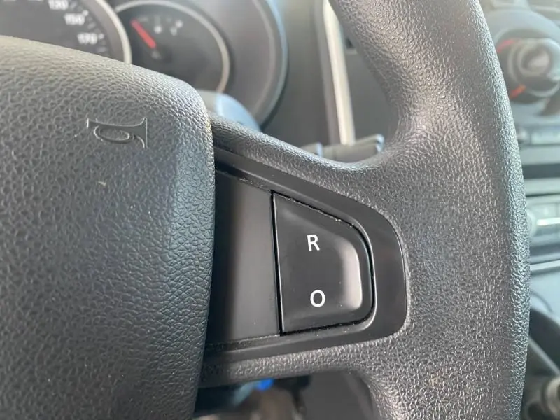 Gros plan sur les commandes vocales R et O sur le volant noir du Renault Kangoo Express 2022, intérieur visible en arrière-plan.
