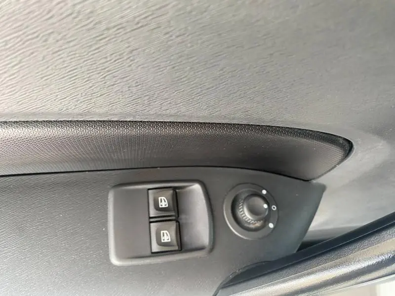 Gros plan sur les commandes de lève-vitres et réglage des rétroviseurs côté conducteur du Renault Kangoo Express blanc 2022.