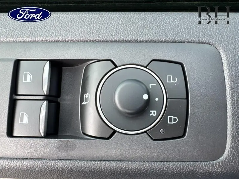 Gros plan sur les commandes de réglage des rétroviseurs et des vitres côté conducteur du Ford Transit Custom gris métallisé.