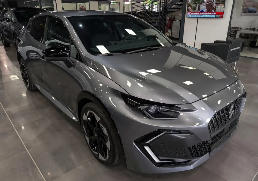 Renault Clio VI TCe 115 gris schiste vue 3/4 avant droit en intérieur, avec jantes noires et calandre distinctive.