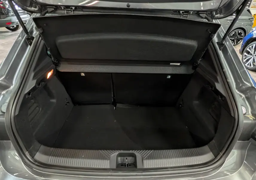 Vue arrière du coffre ouvert de la Renault Clio VI TCe 115 CH TECHNO gris schiste, montrant un espace de rangement vide et propre.