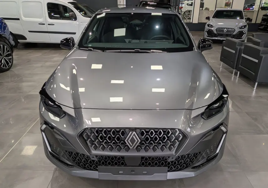 Vue frontale d'une Renault Clio VI TCe 115 CH TECHNO gris schiste, avec calandre hexagonale et phares LED marqués.