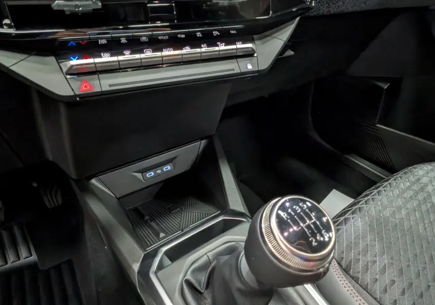 Gros plan sur la console centrale de la Renault Clio VI TCe 115 gris schiste, avec levier de vitesse manuel et commandes climatisation.
