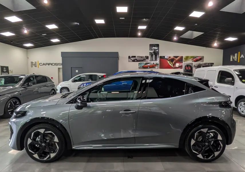 Renault Clio VI TCe 115 Gris Schiste vue de profil côté gauche en intérieur avec jantes noires et toit noir.
