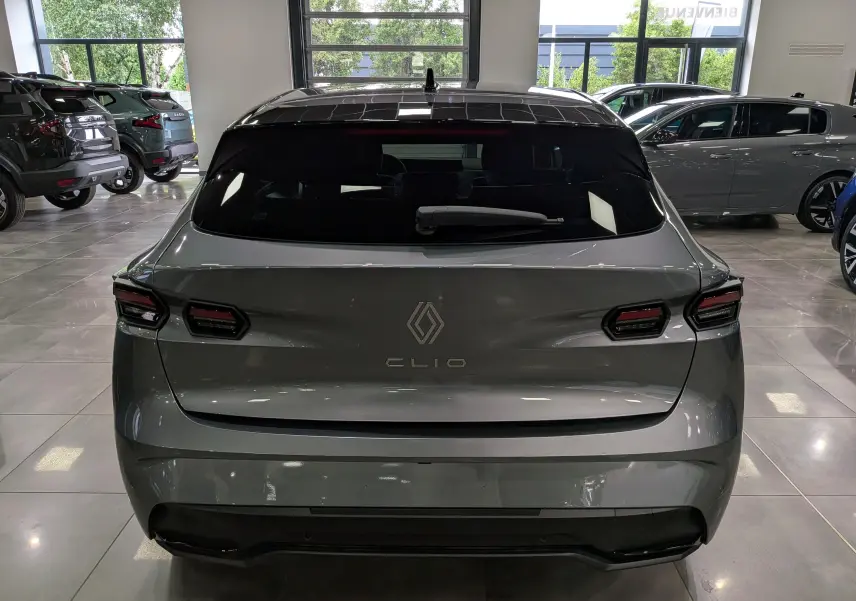 Vue arrière d'une Renault Clio VI TCe 115 CH TECHNO gris schiste, avec feux arrière LED et lunette arrière teintée.
