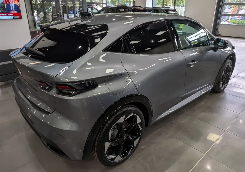 Vue 3/4 arrière droite d'une Renault Clio VI TCe 115 gris schiste avec toit noir et jantes bicolores en concession.