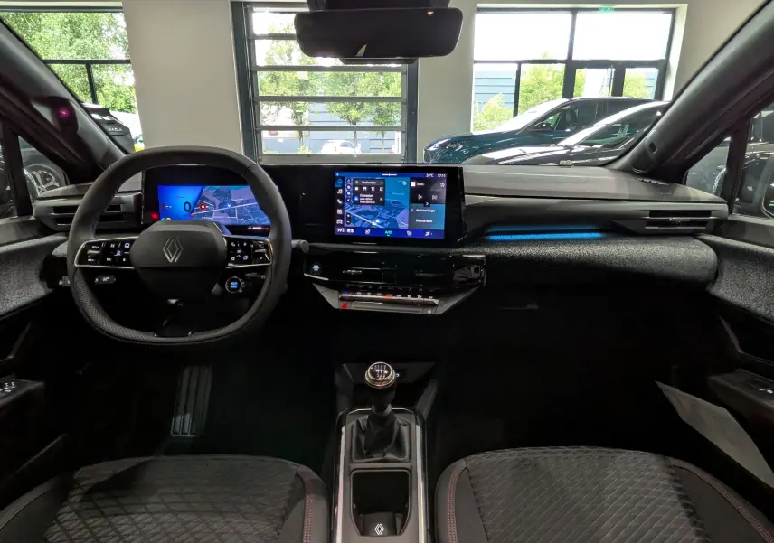 Vue intérieure avant de la Renault Clio VI TCe 115, tableau de bord moderne avec écran tactile et volant multifonction.